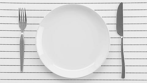 An image of a white plate is centered on a striped placemat with a fork on the left and a knife on the right.