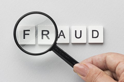 A magnifying glass held above the word 'fraud'. 
