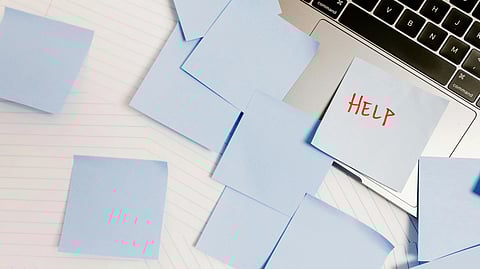 An image of post it notes scattered over laptop and help written on one of them.