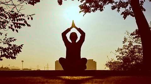 An image of a woman practicing yoga in a park in the early morning.