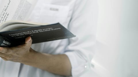 medical student wearing a white court and holding a file.