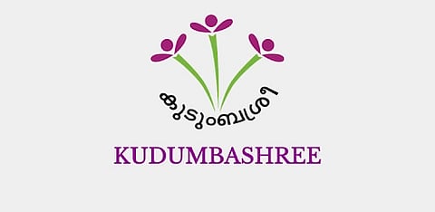 Logo of Kudumbashree in purple and green color which looks like 3 flowers. 