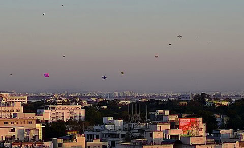 A scene of Kite surfing in the sky from rooftops in a city. 