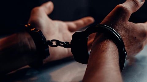 Close-up of a person’s hands being handcuffed on a table.