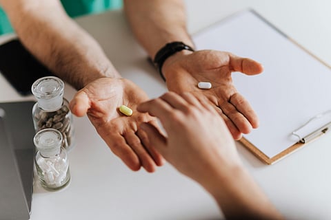 a person holding two tablets in his two palms. The other person is choosing one tablet.
