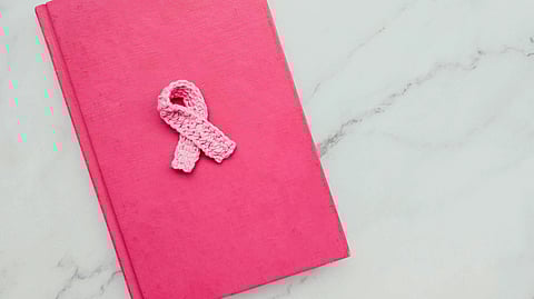 A pink-colored book with a delicate crocheted ribbon in pink color placed on its cover.