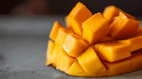 Cubed, ripe mango arranged on a gray surface.