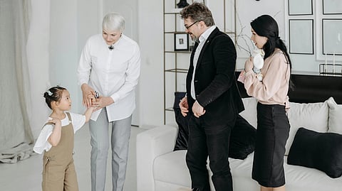 A kid standing next to a doctor and her family standing in front of her.