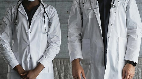 Two doctors standing beside each other, stethoscope around neck. 