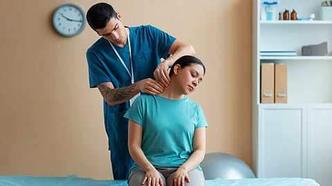 A chiropractor helping a patient with neck movement.