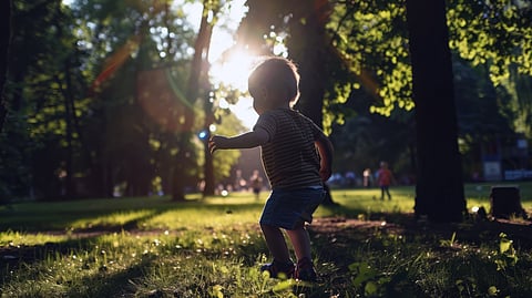 A toddler in a shadow playing outdoors.