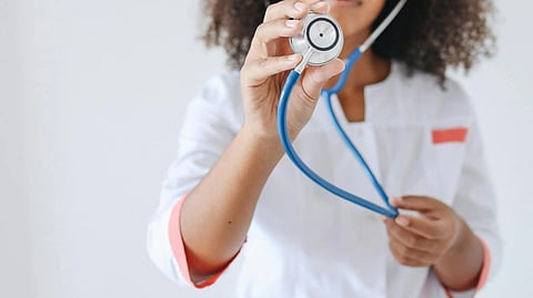 A doctor holding a stethoscope in blue.