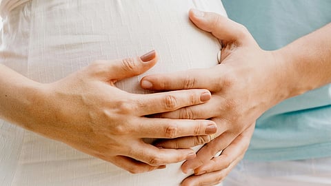 Close-up of a pregnant woman's belly having her and her husband's hands over it.