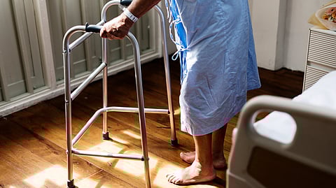 A person in a hospital gown uses a walker.