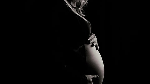 Black and white illustration of a pregnant woman gently resting her hands on her belly.