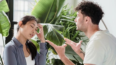 A couple arguing, with the woman in a grey t-shirt and the man in a white t-shirt.