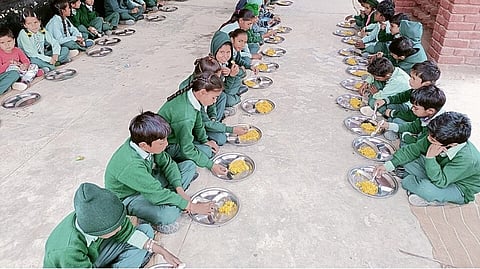 Kids in green uniform and eating food.