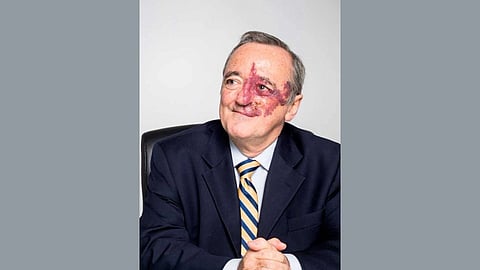 Portrait of Dr. Mariano Barbacid wearing a black formal suit, white shirt, and striped tie, smiling at the camera.