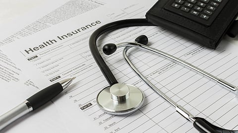 Stethoscope and pen on a health insurance form, with a calculator nearby.