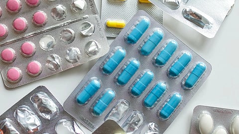 Different strips of medicine in blue, pink, and yellow arranged together on a white background.