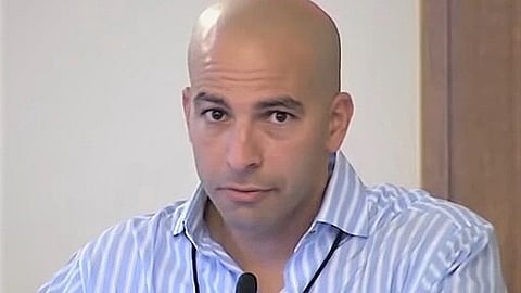 Close-up portrait of Dr. Peter Attia wearing a blue striped shirt, looking directly at the camera.