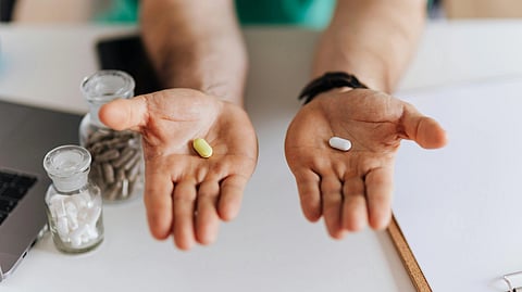 Close-up of a person’s hands with yellow and white clothing, shown against a neutral background.