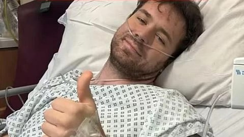 An image of Chris Kirt in a hospital gown with a nasal tube for breathing. 