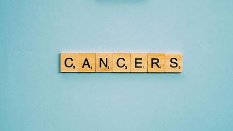 Wooden blocks spelling the word “cancer” arranged in the foreground against a blue background.