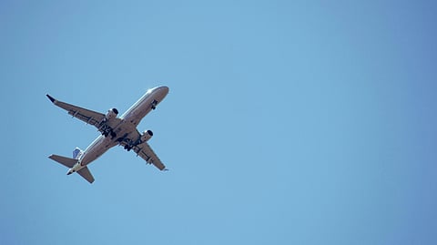 An airplane flying high in a clear blue sky, far in the distance.