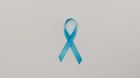 A bright blue ribbon, shaped into a loop, lies centered on a plain light gray background.