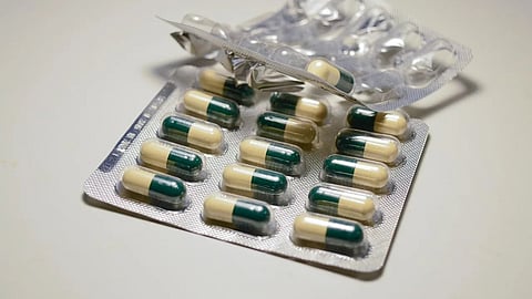 Antibiotic capsules in a strip on a white surface, highlighting concerns about antibiotic resistance.