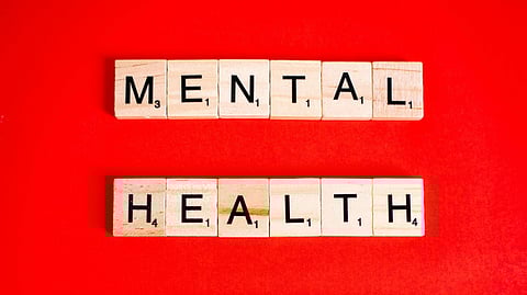 Illustration showing mental health written on wooden blocks in front of a red background.