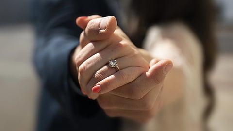 A couple showing their hands with the lady wearing the engagement ring. 