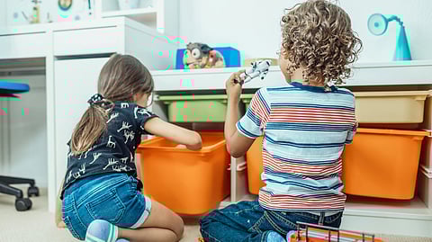 Two children are playing indoors with toys.