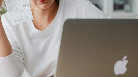 Close-up of a woman in a white T-shirt working on a laptop.