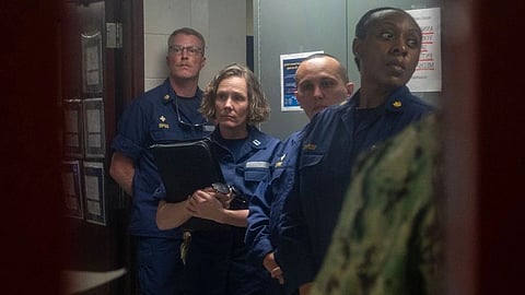 Four uniformed Coast Guard officers stand together.
