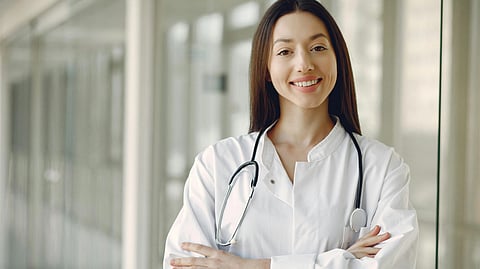 A female doctor in white coat and stethoscope around neck.
