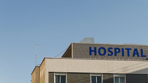 A hospital building with the word “HOSPITAL” displayed prominently against a clear blue sky.