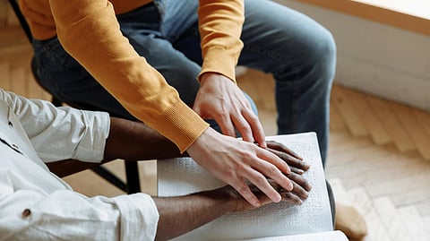 2 men sitting together one man's hand over another's.