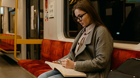 A girl sitting on a train journaling in a diary