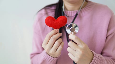 A child holding a heart and stethoscope in hand.
