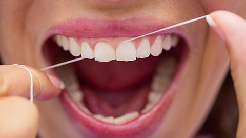A close-up of a female flossing her teeth.