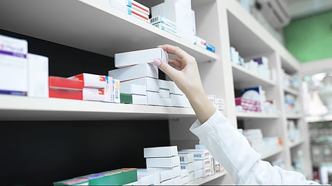Closeup view of pharmacist hand taking medicine box from the shelf in drug store

