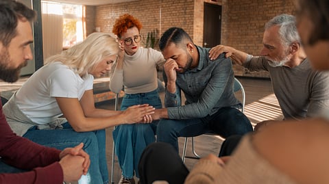 A group of people sitting in a circle, showing support and care.
