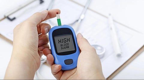 Hand holding a blood glucose meter measuring blood sugar, the background is 