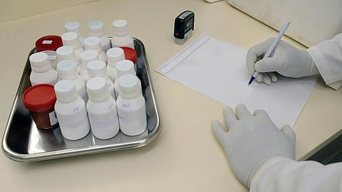 A pathologist signing a paper and samples kept in front.