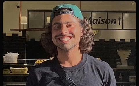 Kiano wearing a black tshirt and a green cap.