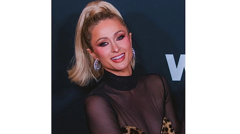 Image of Paris Hilton with blonde hair and a high ponytail, wearing a sheer black top with leopard print accents.