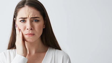 A woman with long hair touches her cheek.