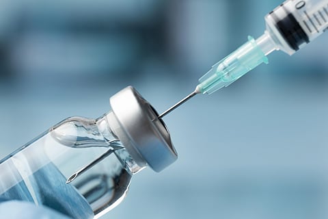 A syringe taking some medication from a vial.